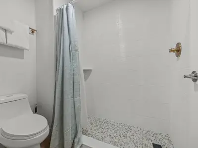 a white bathroom with a shower and a toilet at Florida vibe suite near Epic Universe & Universal in Orlando