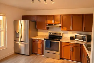 a kitchen with wooden cabinets and a stainless steel refrigerator at Family Retreat - 9 Min from Disney in Kissimmee