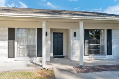 a white brick house with a black door at Spacious home w screened patio & EV charger in Orlando