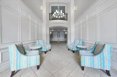 a waiting room with blue chairs and a chandelier at Epic Universe Condo - Vista Cay - 2028 in Orlando