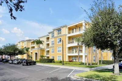 a large yellow apartment building with a parking lot at Epic Universe Condo - Vista Cay - 2028 in Orlando