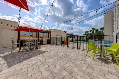 a patio with tables and chairs and a pool at Home2 Suites by Hilton Orlando International Drive South - Free Shuttle to Theme Parks in Orlando
