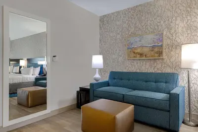 a living room with a blue couch and a bed at Home2 Suites by Hilton Orlando International Drive South - Free Shuttle to Theme Parks in Orlando