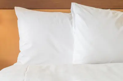 a bed with white sheets and pillows on it at Holiday Inn Express & Suites S Lake Buena Vista by IHG in Kissimmee