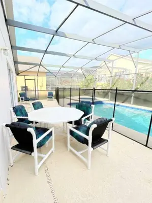a patio with a table and chairs and a pool at Clermont Vacation Homes by DWS Vacation in Orlando
