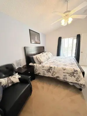 a bedroom with a bed and a couch and a ceiling fan at Clermont Vacation Homes by DWS Vacation in Orlando
