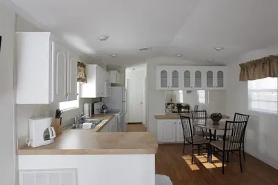 a kitchen with white cabinets and a table and chairs at Sherwood Forest Cottage 6 in Kissimmee
