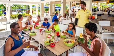 a group of people sitting at a table eating food at The Grove Resort & Water Park Orlando in Orlando