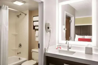 a bathroom with a sink and a toilet and a mirror at Ramada by Wyndham Suites Orlando Airport- Free Airport Shuttle in Orlando
