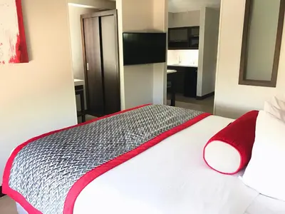 a bedroom with a white bed with a red and black blanket at Ramada by Wyndham Suites Orlando Airport- Free Airport Shuttle in Orlando
