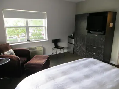 a bedroom with a bed and a chair and a television at The EO Inn - Downtown Orlando in Orlando