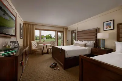 a hotel room with two beds and a table with a chair at Arnold Palmer's Bay Hill Club & Lodge in Orlando