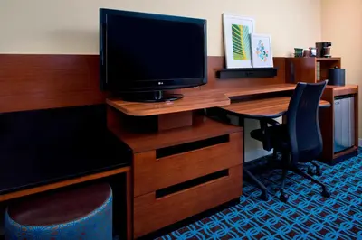 a desk with a television and a desk with a chair at Fairfield Inn & Suites by Marriott Orlando Lake Buena Vista in the Marriott Village in Orlando
