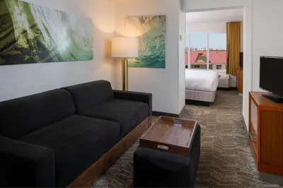 a living room with a couch and a room with a bed at SpringHill Suites by Marriott Orlando Convention Center in Orlando