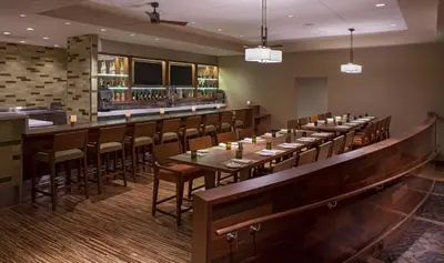 a restaurant with long tables and chairs and a bar at Hyatt Regency Orlando International Airport Hotel in Orlando