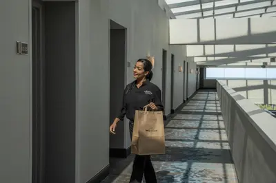 a woman walking down a hallway with a paper bag at Hyatt Regency Orlando International Airport Hotel in Orlando
