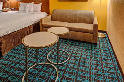 a hotel room with a bed and a couch and tables at Fairfield Inn and Suites by Marriott Orlando Near Universal Orlando in Orlando