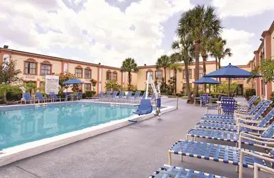 a resort pool with blue chairs and a building at La Quinta Inn by Wyndham Orlando International Drive North in Orlando