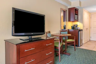 a room with a flat screen tv on a dresser with a table at Holiday Inn Resort Orlando - Lake Buena Vista by IHG in Orlando