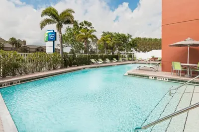 a pool at a hotel with chairs and an umbrella at Holiday Inn Express & Suites - Nearest Universal Orlando by IHG in Orlando