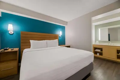 a bedroom with a large white bed and a sink at Sonesta ES Suites Orlando International Drive in Orlando