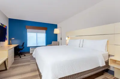 a bedroom with a white bed and a blue wall at Holiday Inn Express-International Drive by IHG in Orlando