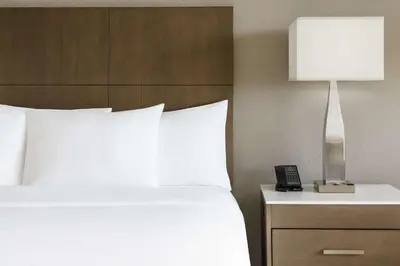 a bed with white sheets and a lamp on a night stand at DoubleTree by Hilton Orlando Airport Hotel in Orlando