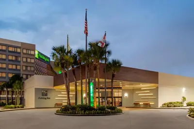 a hotel with palm trees in front of a building at Holiday Inn Orlando International Airport by IHG in Orlando