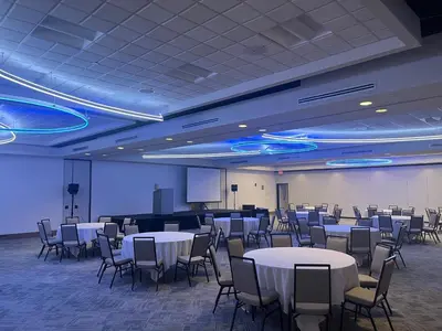 a conference room with tables and chairs and a screen at Holiday Inn Orlando International Airport by IHG in Orlando