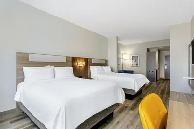 a hotel room with two beds and a yellow chair at Holiday Inn Express Orlando-Ocoee East by IHG in Orlando