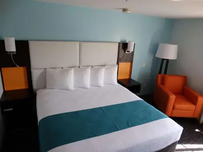 a bedroom with a bed and an orange chair at Best Western Plus Orlando Lake Buena Vista South Inn & Suites in Kissimmee