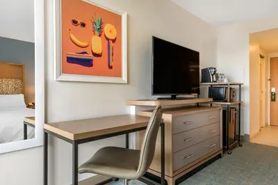 a room with a desk with a computer and a television at Holiday Inn Orlando – Disney Springs® Area by IHG in Orlando