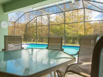 a table and chairs in front of a swimming pool at 3 Bed 258 in Kissimmee