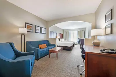 a hotel room with blue chairs and a bed at Comfort Suites Downtown in Orlando