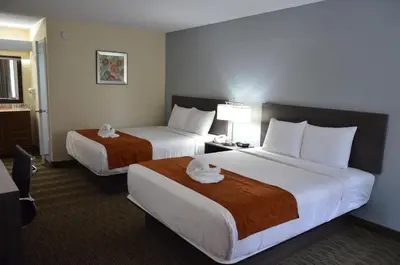 a hotel room with two beds with towels on them at Days Inn & Suites by Wyndham Orlando Airport in Orlando