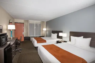 a hotel room with two beds and a television at Days Inn & Suites by Wyndham Orlando Airport in Orlando