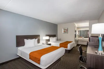 a hotel room with two beds and a desk at Days Inn & Suites by Wyndham Orlando Airport in Orlando