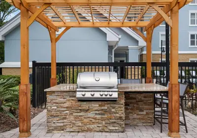 a barbecue under a wooden pergola on a patio at Homewood Suites by Hilton Lake Mary Orlando North in Lake Mary