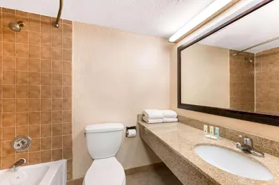 a bathroom with a toilet and a sink and a mirror at Quality Inn & Suites Orlando Airport in Orlando