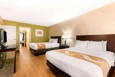 a hotel room with two beds and a flat screen tv at Quality Inn & Suites Orlando Airport in Orlando