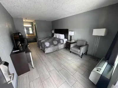 a hotel room with a bed and a chair at Budget Inn Sanford International Airport in Sanford