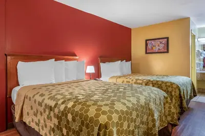 two beds in a hotel room with red walls at Econo Lodge Inn & Suites Maingate Central in Kissimmee