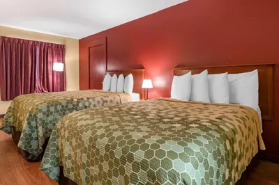 two beds in a hotel room with red walls at Econo Lodge Inn & Suites Maingate Central in Kissimmee