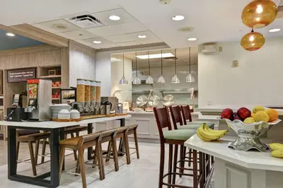 a kitchen with a table with chairs and fruits on it at Hilton Garden Inn Orlando Lake Buena Vista in Orlando