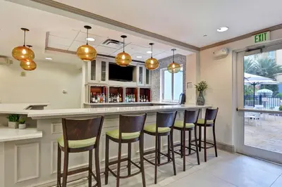 a bar with stools in a kitchen with a patio at Hilton Garden Inn Orlando Lake Buena Vista in Orlando