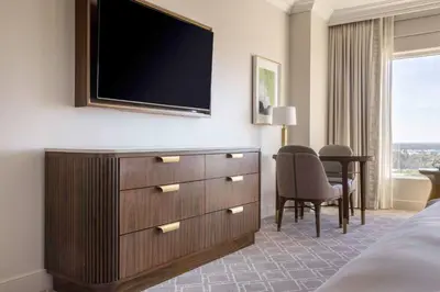 a bedroom with a dresser with a television on a wall at Waldorf Astoria Orlando - An Official Walt Disney World Hotel in Orlando