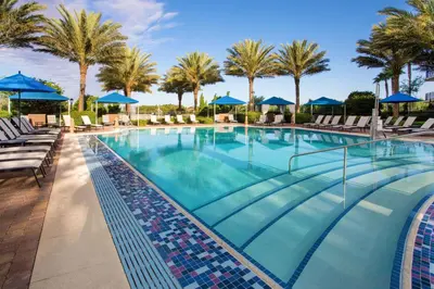 a large swimming pool with chairs and palm trees at Hilton Grand Vacations Club Parc Soleil Orlando in Orlando