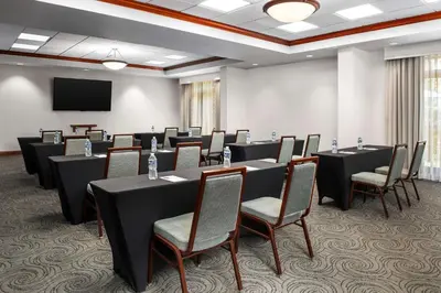 a conference room with tables and chairs and a screen at Hampton Inn & Suites at Lake Mary Colonial Townpark in Lake Mary
