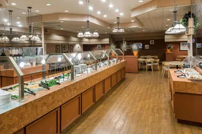 a restaurant with a buffet line with tables at Ramada by Wyndham Kissimmee Gateway - Free Theme Park Shuttle in Orlando