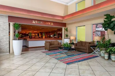 a lobby of a hotel with couches and plants at Ramada by Wyndham Kissimmee Gateway - Free Theme Park Shuttle in Orlando